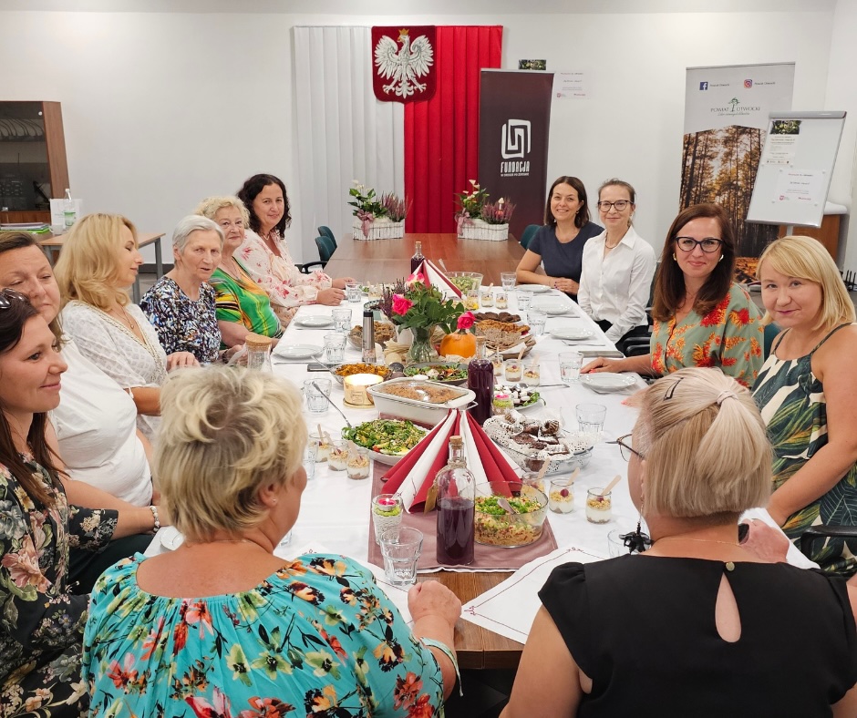 Uczestniczki programu Żyj Zdrowo w Kołbieli, wspólnie celebrujące zakończenie programu przy stole z kolorowymi i zdrowymi potrawami.